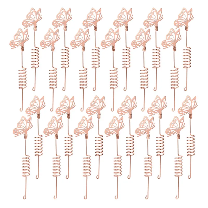 Twenty-four copper butterfly stakes with coiled stems laid out in two rows on a white background